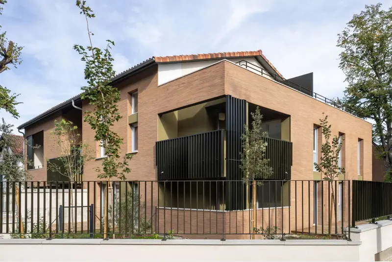 Maison de brique aux balcons à claustras noirs